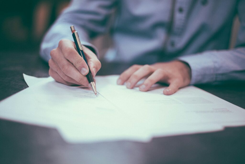 A person signing application paperwork at a desk