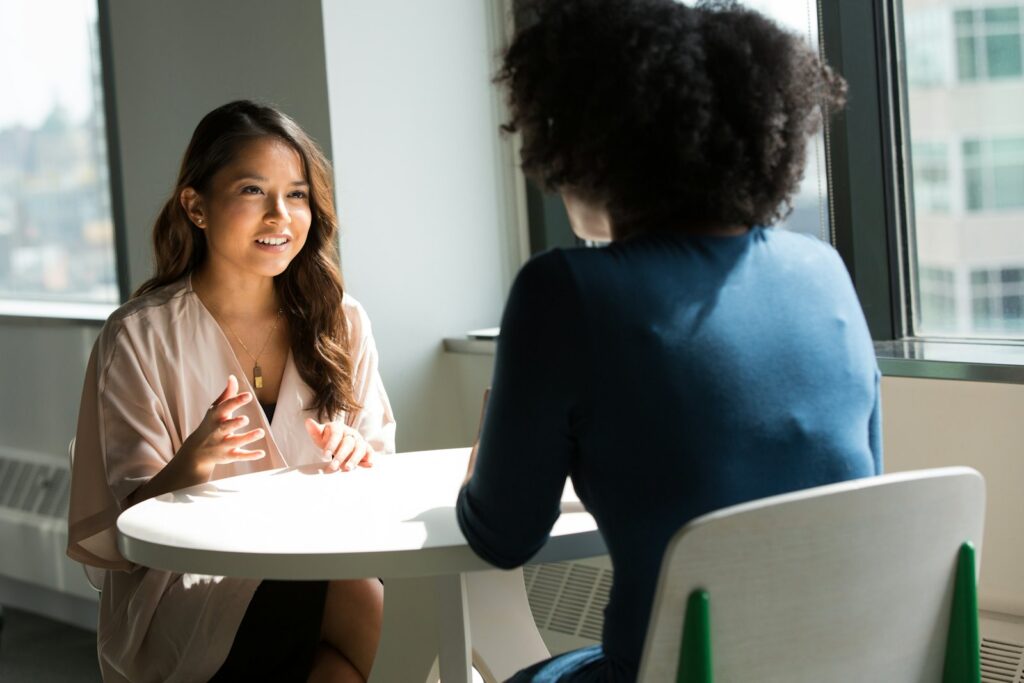 Two people talking across a table in an interview setting