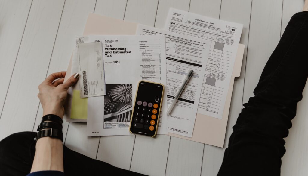 A person reviewing financial documents with a pen and calculator